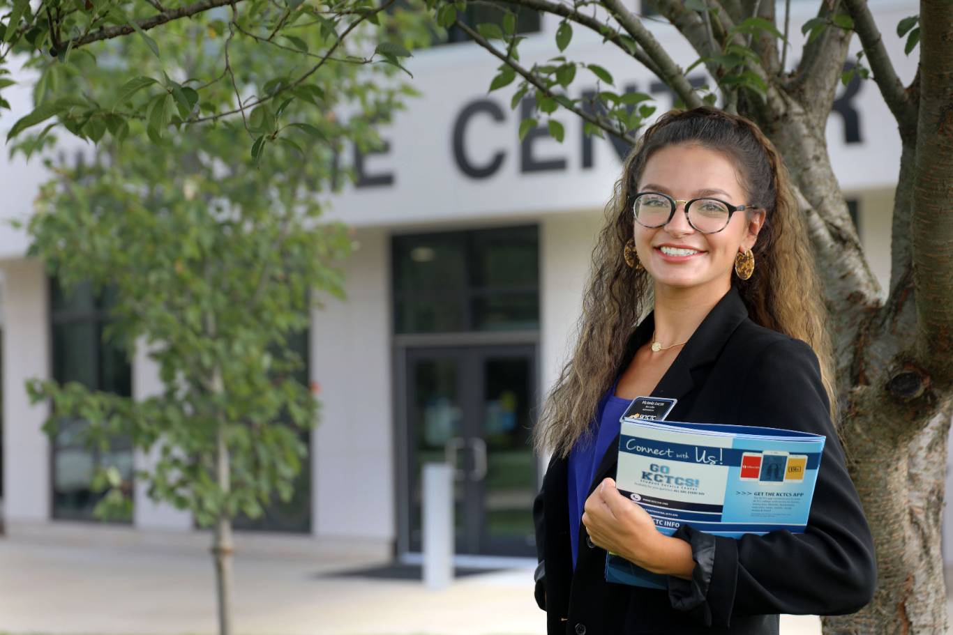 Individual holding folders standing in front of building